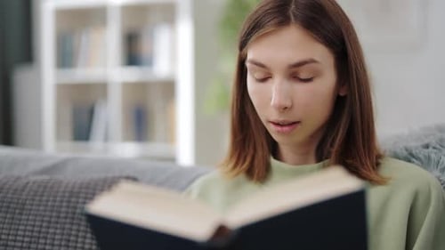 Woman Reads Book While Sitting on Gray Couch