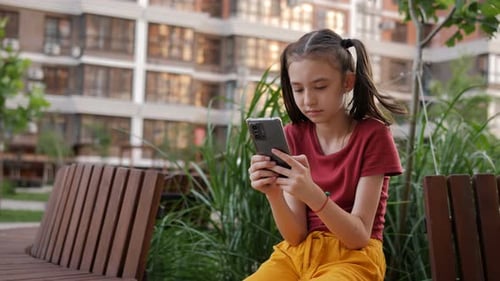 Girl Using Smartphone on Bench Outside