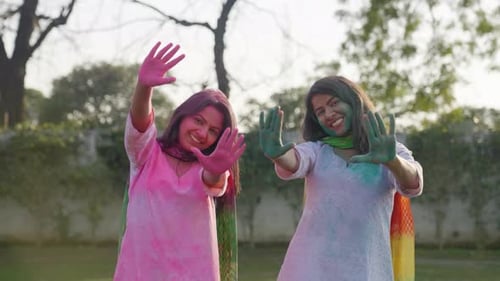 Happy and smiling Indian girls showing colored hands to the camera on Holi occasion