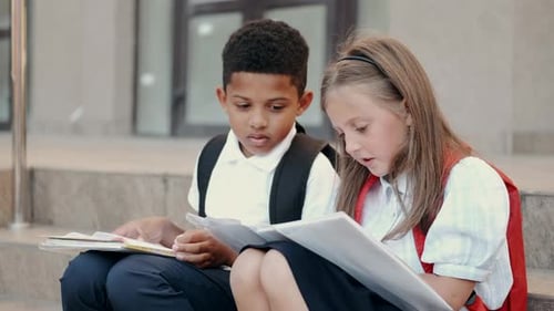 Schulkinder lesen Buch, während sie auf der Treppe sitzen