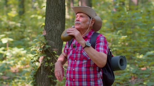 Tired Thirsty Senior Old Caucasian Hiker Grandfather Relaxing Drinking Water in Forest After Walk