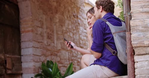 Two Tourists Using Smartphone To Search Amenities or Landmarks in Rural town.Medium Shot Side View
