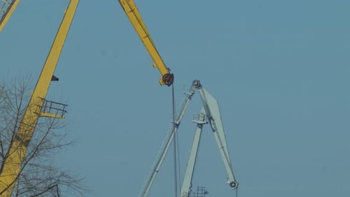 Sea port crane loading cargo in sunny, warm day, telephoto medium closeup shot from distance