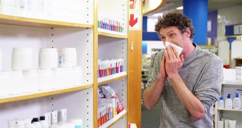 Cliente verificando a caixa de medicamentos enquanto espirra