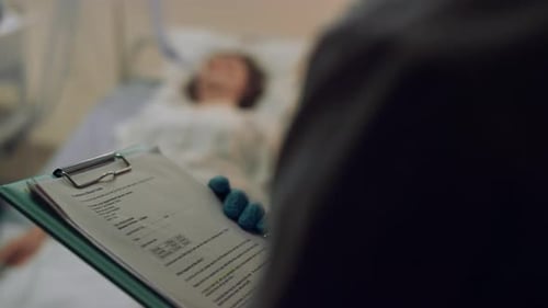 Medical Professional Writes on Clipboard in Hospital