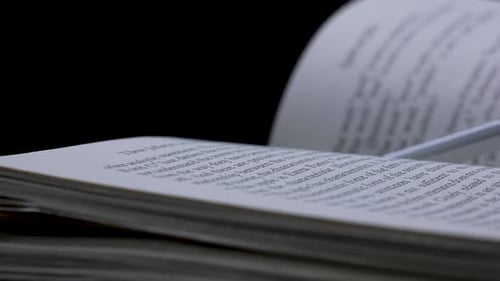 An Open Book Lies in a Dark Studio on a Black Background