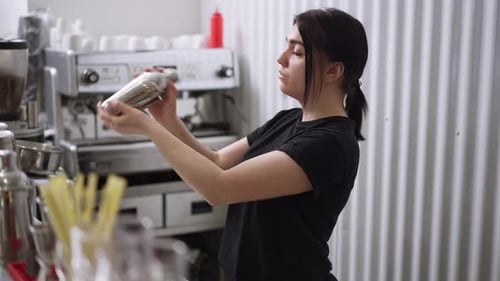 Side View Concentrated Professional Female Bartender Shaking Cocktail Shaker in Slow Motion