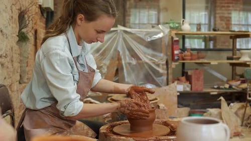 Young Woman Shaping Clay on Potter's Wheel