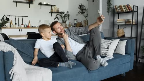 Father and Son Taking Selfie on Couch at Home