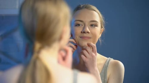Woman Smiling at Her Reflection in a Mirror