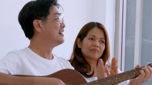 Man Plays Guitar as Woman Claps Along