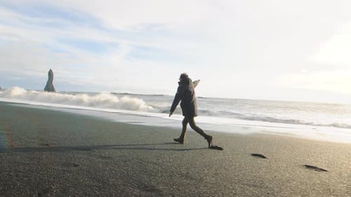 Man Running Like a Plane on Volcanic Black Sand Beach in Iceland