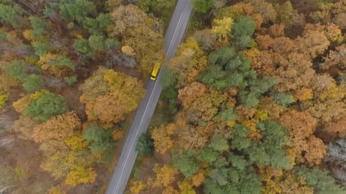 Drone Following Yellow Bus or Truck Speeding on Mountain Road in the Autumn