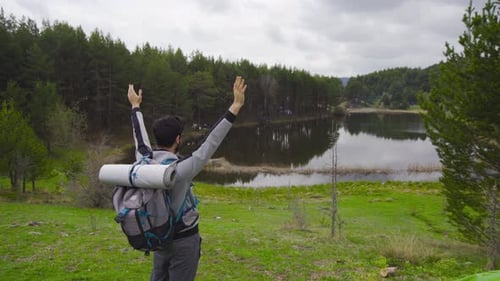 Man Enjoying Scenic Lake View with Arms Raised