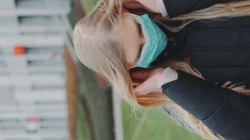 Woman Puts on a Medical Mask Outdoors