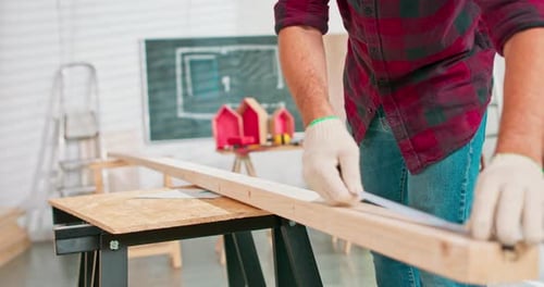 Man Measures Wood in Workshop