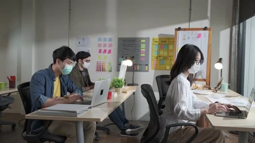 Asian creative business team working at office after lockdown with protective prevention face mask.
