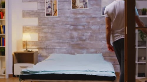 Man Prepares for Sleep in Cozy Bedroom at Night