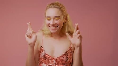 Woman Crossing Fingers on a Pink Background