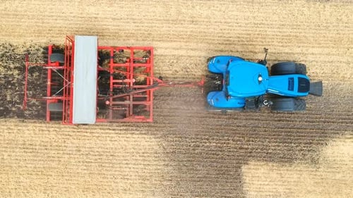 Aerial Shot of Tractor Plowing Ground at Field. Flying Over Agricultural Machine Working on Farm