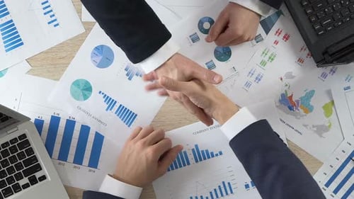 Business Professionals Handshake Over Data Charts