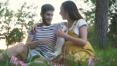 Loving Couple Plays with Dog at Summer Picnic