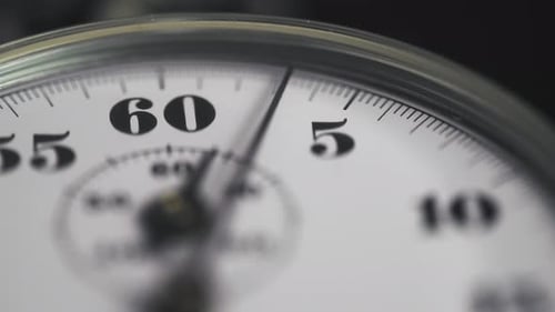 Cronómetro analógico mecánico retro sobre un fondo oscuro, cuenta regresiva los segundos.