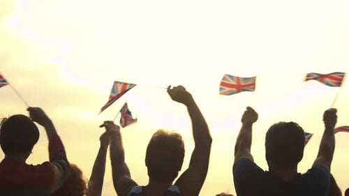 People Waving Union Jack Flags at Sunset