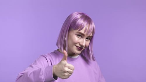 Pretty Woman Showing Thumb Up Like Sign Over Violet Studio Background