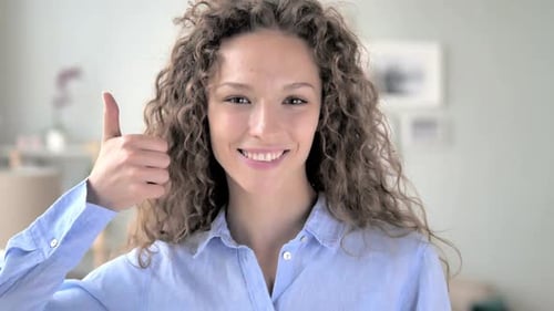 Smiling Young Woman Giving a Thumbs Up Indoors