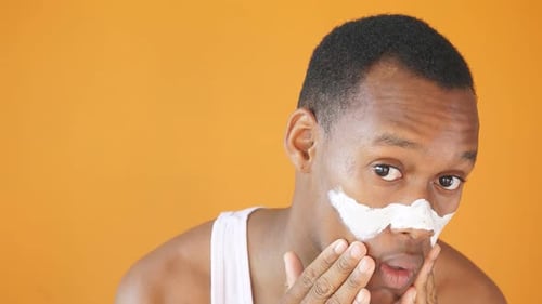 Man Applying Cream to Face and Smiling