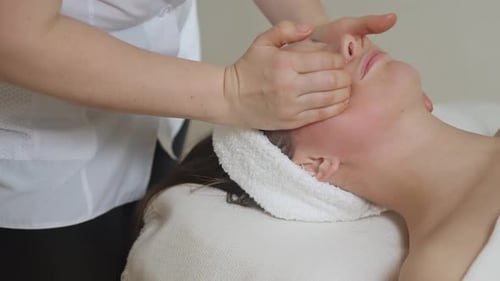 Cute Brunette Woman on Face Massage in Spa Salon