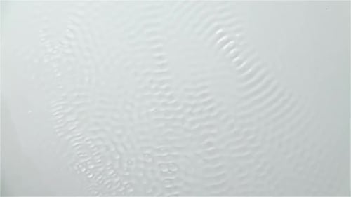 Die
Reflexion des Wassers erzeugt Wellen, die durch Vibration verursacht werden. Weißer Hintergrund. Zeitlupe