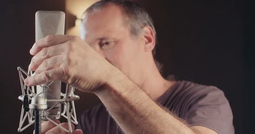 Sound engineer working in a recording studio with a sound console and microphones