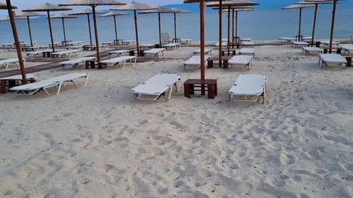 Empty beach with sunbeds and wooden umbrellas on the mediterranean sea.