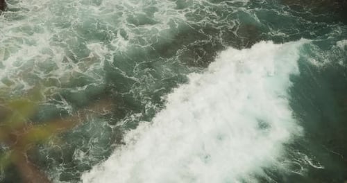 Close Up Slow Motion View of the Wave Moving on the Water and Crashing Ashore the Rocky Tropical