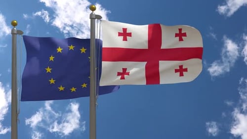 European Union and Georgian Flags Waving Together in Blue Sky
