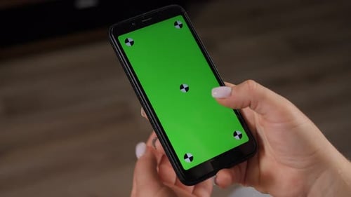 Closeup of Woman's Hand Browsing Smartphone with Green Screen at Home