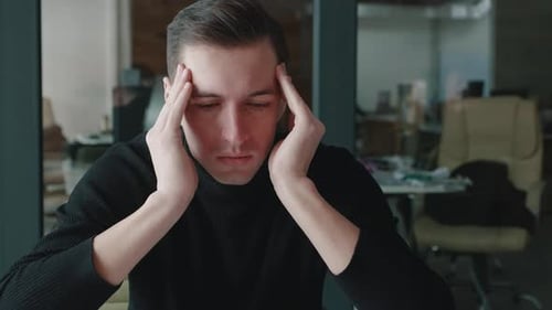 Worried man with headache in office environment