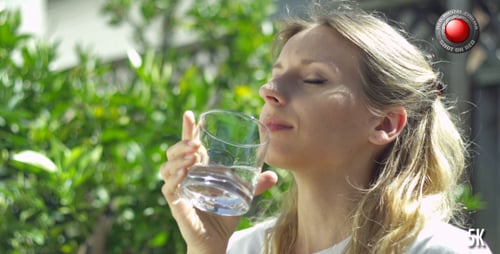 Woman Drinking Water Outdoors on a Sunny Day