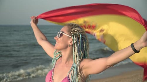 Woman Waves Spanish Flag on Sandy Beach