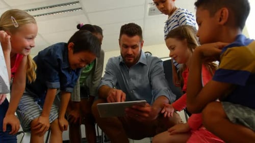 Adult Caucasian male teacher teaching school kids on digital tablet in classroom 4k