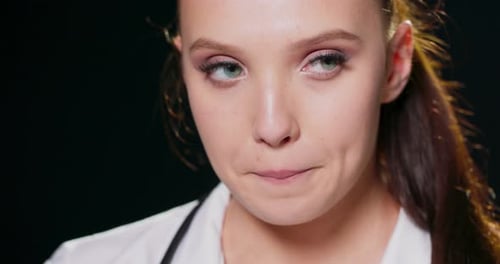 Closeup on the Face of a Worried Young Woman Against a Black Studio Background with Copy Space