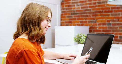 Young Woman Works on Laptop and Phone