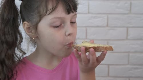 Child Eating Buttered Bread Slice Indoors