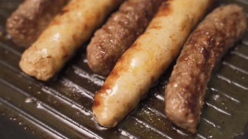 Sizzling Sausages Cooking on a Grill Pan