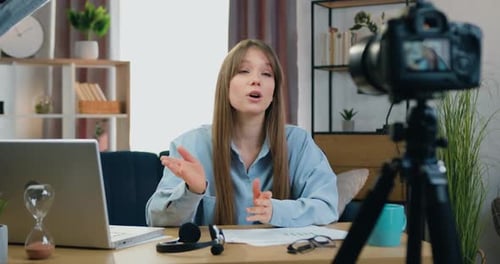 Woman Presenting to Camera at Desk Indoors