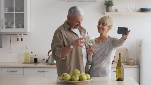 Loving Mature Couple Taking Selfie with Wine in Kitchen