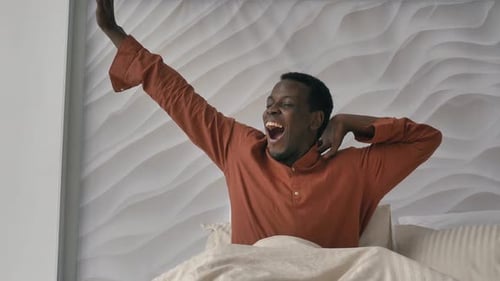 Un homme afro-américain se réveille et sort du lit le matin