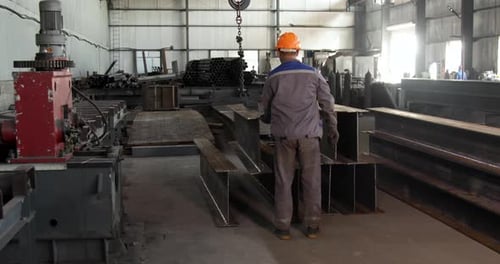 Trabajador recibe una barra de metal de una grúa en el almacén